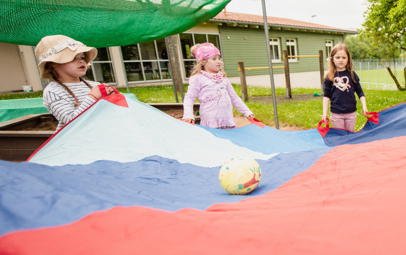 Kinder spielen mit buntem Schwungtuch